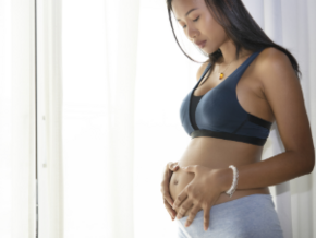 Mujer embarazada parada, sosteniendo su vientre y con cara de preocupación por sangrado en el embarazo.