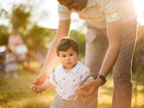 Adulto ayudando a un niño pequeño a caminar.