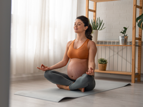 Mujer embarazada practicando yoga en casa.