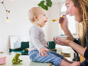 ¿Por qué son tan importantes los probióticos en niños? Mamá alimentando con una cuchara a su hijo pequeño con probióticos.