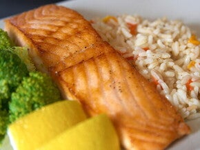 Plato con salmón a la parrilla, arroz con verduras, brócoli y rodajas de limón,