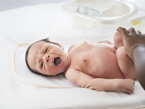 Mujer al aire libre sonriendo y dando pecho a su bebé.