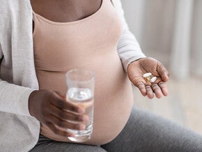 Mujer embarazada tomando vitaminas prenatales