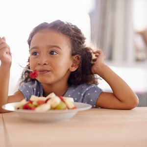 Niña vegetariana comiendo un plato de frutas