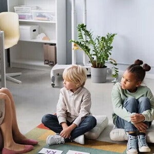 ¿Qué es la Apraxia del Habla Infantil? Patólogo del habla y lenguaje, SLP terapeuta del habla y lenguaje, fonoaudiólogo mostrando abecedario a niños pequeños sentados sobre cojines.