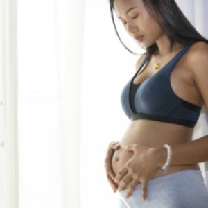 Mujer embarazada parada, sosteniendo su vientre y con cara de preocupación por sangrado en el embarazo.