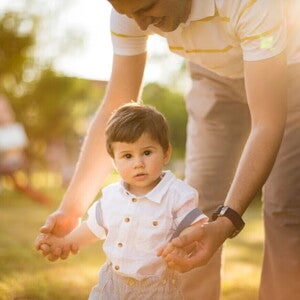 Consejos para estimular los primeros pasos del bebé Adulto ayudando a un niño pequeño a caminar.