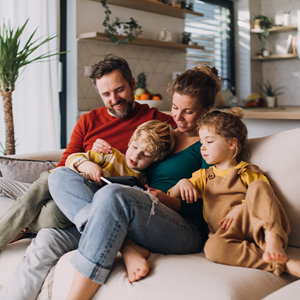 Familia sentada en un sofá en una sala de estar, leyendo un libro