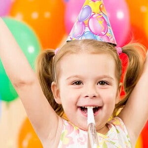Guía para fiestas infantiles Niña pequeña feliz en una fiesta infantil con globos de colores.