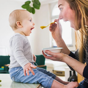 ¿Por qué son tan importantes los probióticos en niños? Mamá alimentando con una cuchara a su hijo pequeño con probióticos.