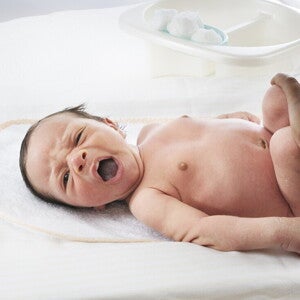 Mujer al aire libre sonriendo y dando pecho a su bebé.