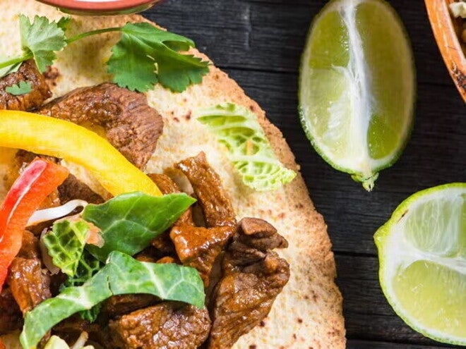 Fajitas rellenas con res y una salsa con limones a un lado