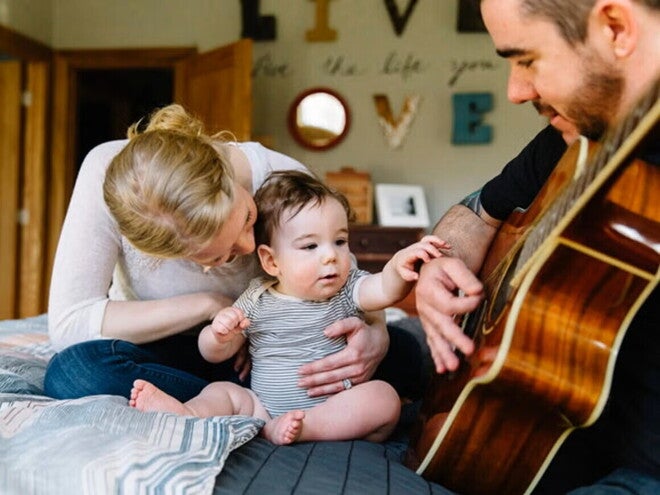 Mamá, bebé y papá tocando la guitarra.