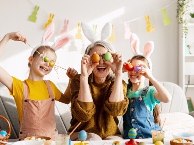 Padres y niños celebrando Pascua, cubriendo sus ojos con huevos de colores de forma divertida.