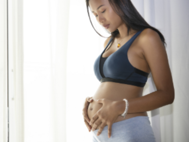 Mujer embarazada parada, sosteniendo su vientre y con cara de preocupación por sangrado en el embarazo.