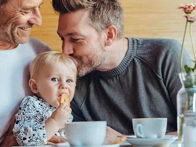 Niña comiendo galletas para bebés con su papá y abuelo.