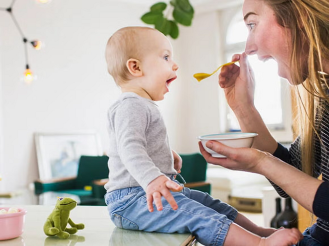 ¿Por qué son tan importantes los probióticos en niños? Mamá alimentando con una cuchara a su hijo pequeño con probióticos.