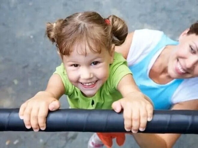 Niña sonriendo jugando en el pasamanos.