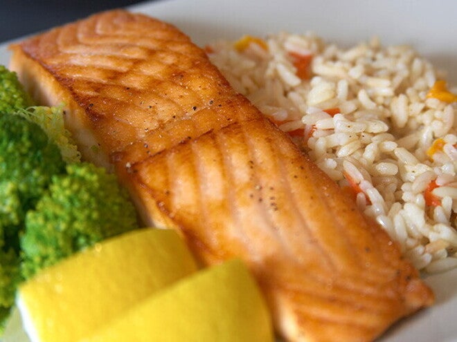 Omega-3 y el rendimiento escolar Plato con salmón a la parrilla, arroz con verduras, brócoli y rodajas de limón,
