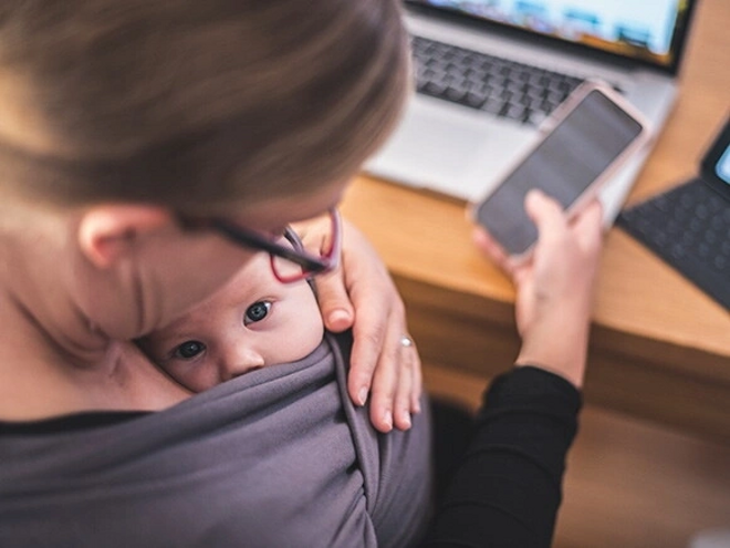 Como lidiar con la culpa parental Madre trabajando con su hijo en brazos