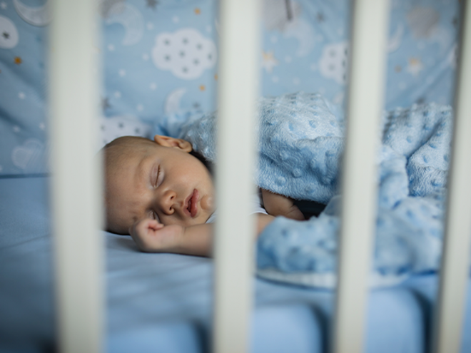 Respiración bucal en bebés Bebé durmiendo plácidamente en una cuna, con la boca ligeramente abierta.
