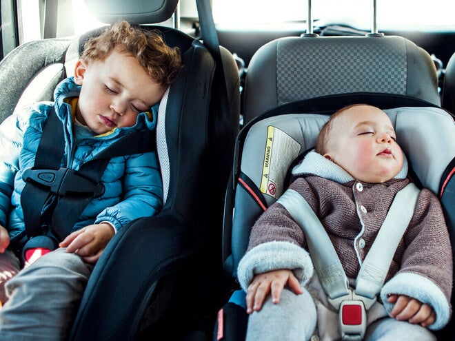 Niño pequeño y bebé durmiendo cada uno en una silla de seguridad para el auto.