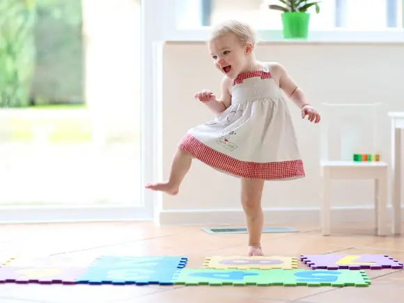 Qué son las actividades sensoriales niña bailando sobre tapetes de goma para jugar