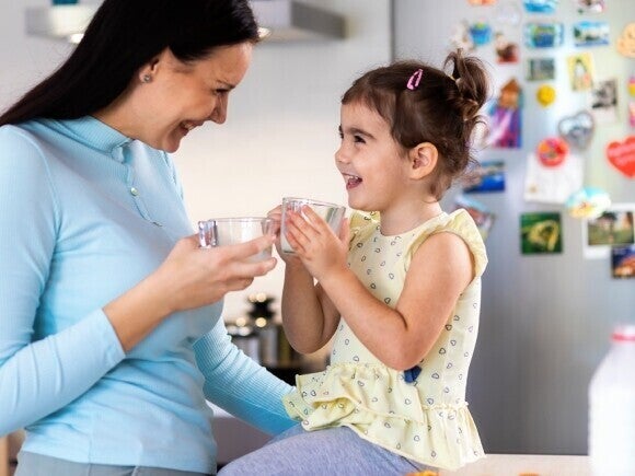Familia con una niña compartiendo una comida en casa, sentados en la cocina y disfrutando juntos.