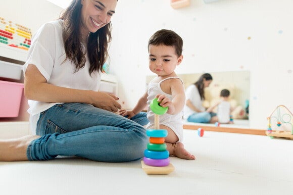Mamá y bebé de 14 meses jugando en el suelo con bloques.
