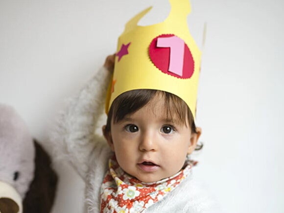 Fiesta infantil: qué tener en cuenta Niña pequeña con una corona de cumpleaños.