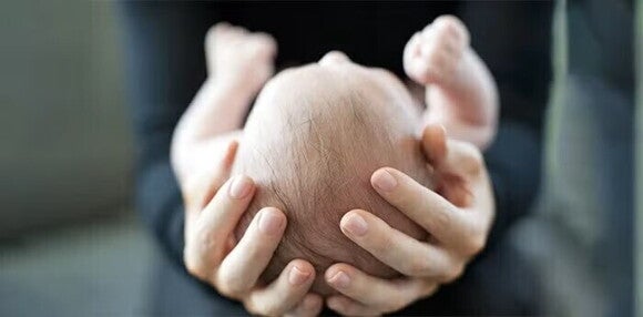 Manos sosteniendo a un bebé. Concepto de crecimiento y desarrollo del bebé.