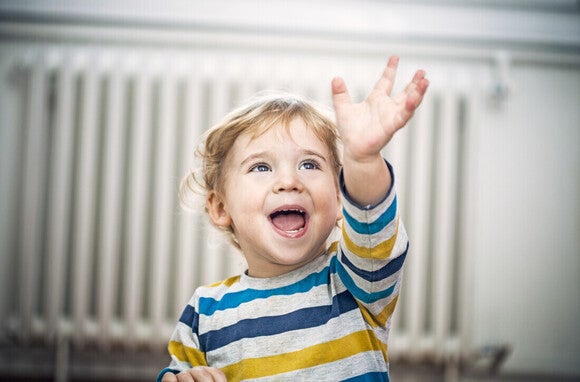Niño pequeño sentado en su habitación saludando y hablando.